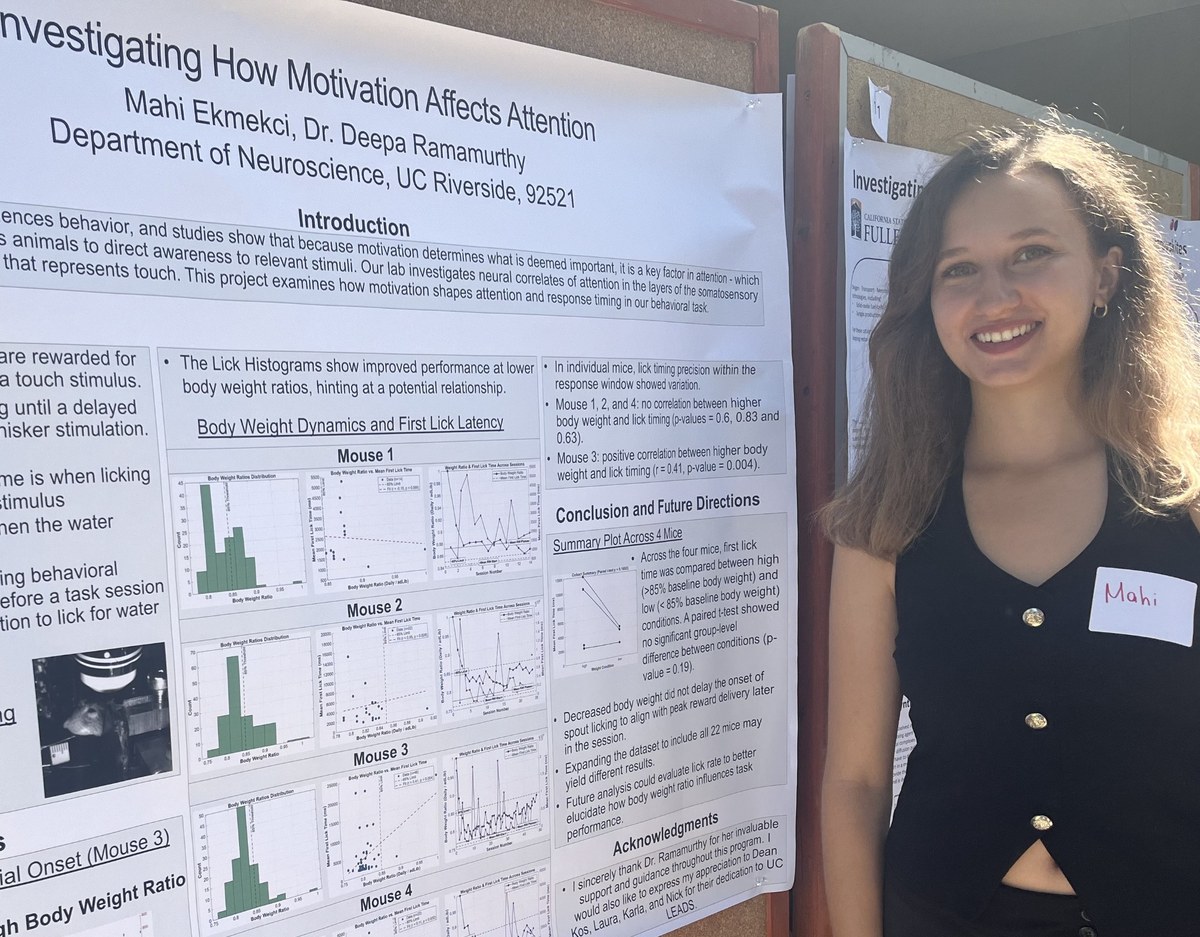 Mahi standing beside a research poster about motivation and attention at the UC LEADS symposium.