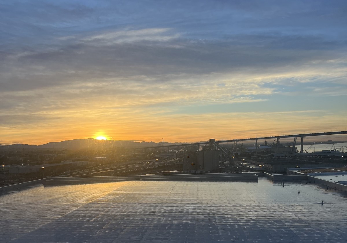 Golden light over San Diego Bay and the Coronado Bridge, viewed from a rooftop pool.