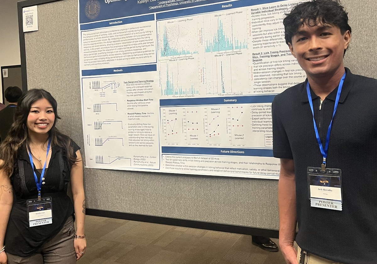 Two student presenters standing beside a research poster at the UCR Undergraduate Research and Creative Activities Symposium.